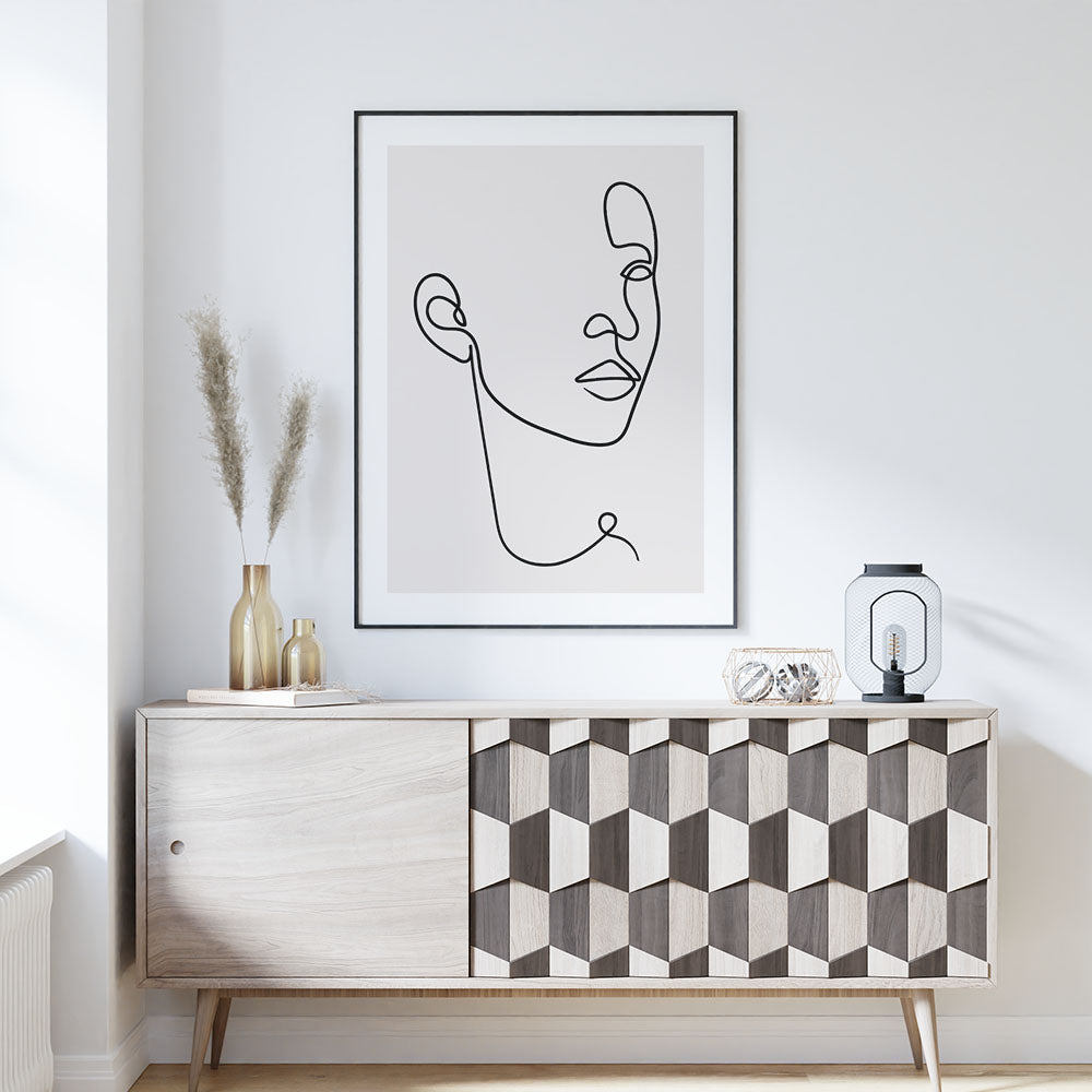 Line art face print framed above a sideboard