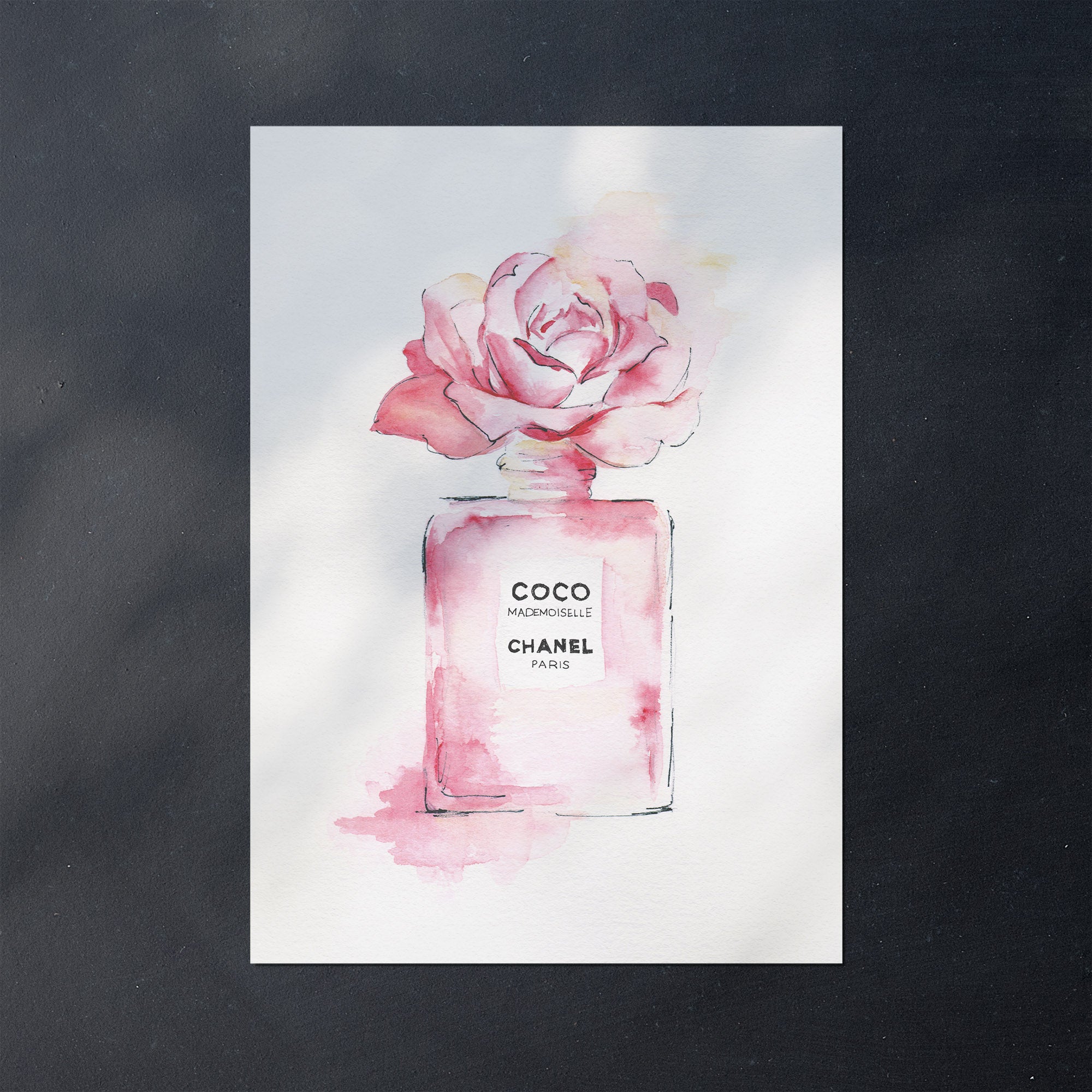 An unframed poster with a Chanel perfume bottle and pink rose